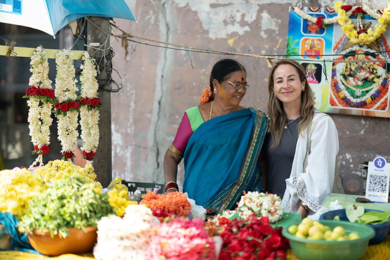 Claudia Moya junto a una vendedora en un mercado de flores de India del Sur