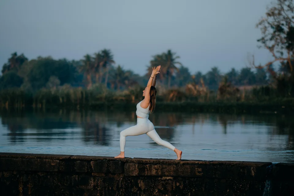 Practicante de Vinyasa Yoga en una postura de guerrero junto al río